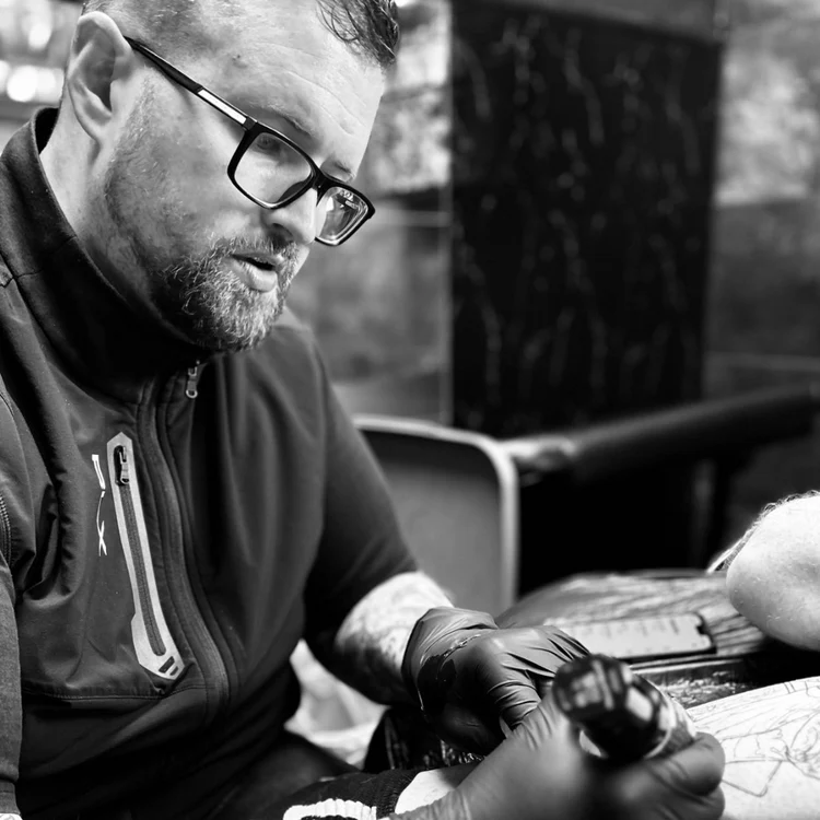 Tattoo artist working on a client’s arm inside Jinked tattoo studio in Porthcawl.